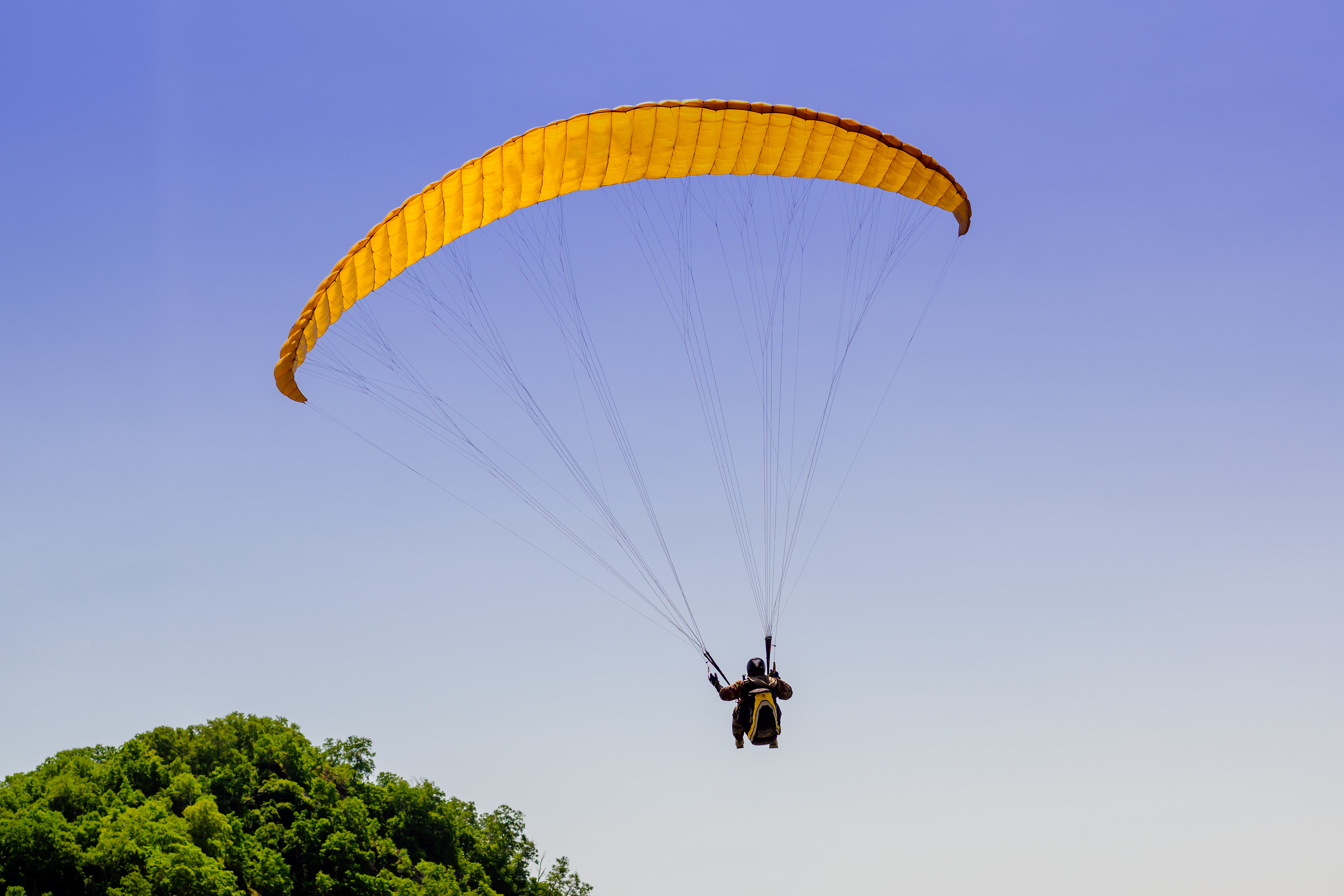 Paragliding above hill in bright summer day